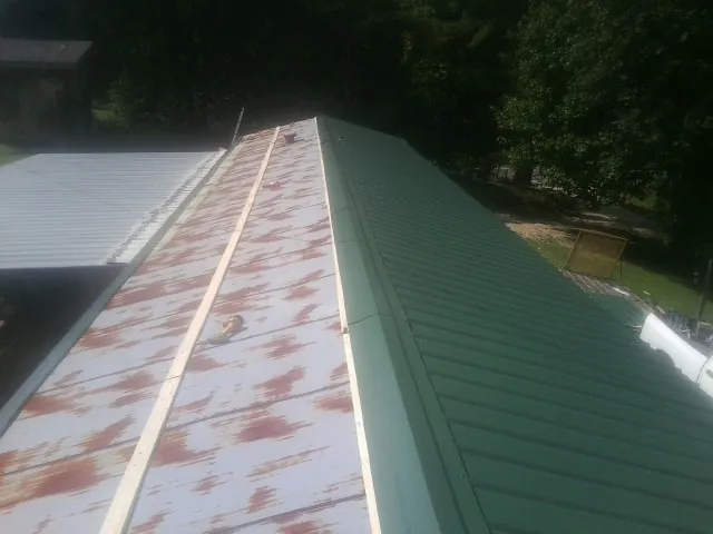 Old rusted panels beside newly installed green metal roofing — Wind Damage Roof Repair by Roofing Brothers in Washington Court House