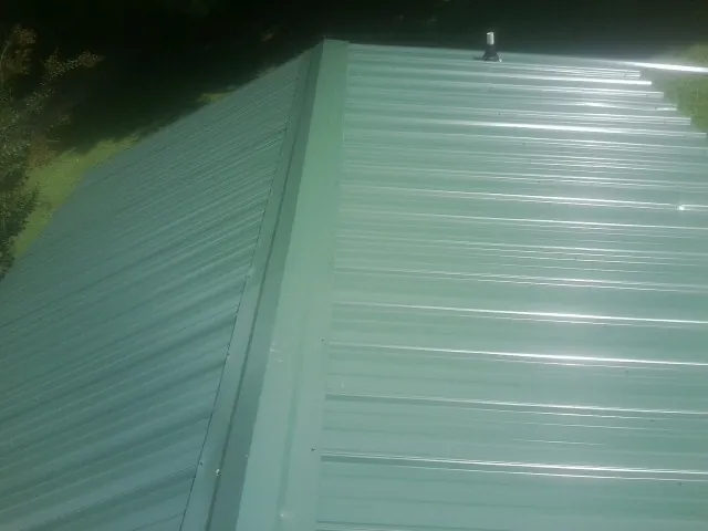 New green metal panels meeting at the ridge of a roof — Flat Roof Repair work by our crew in Washington Court House