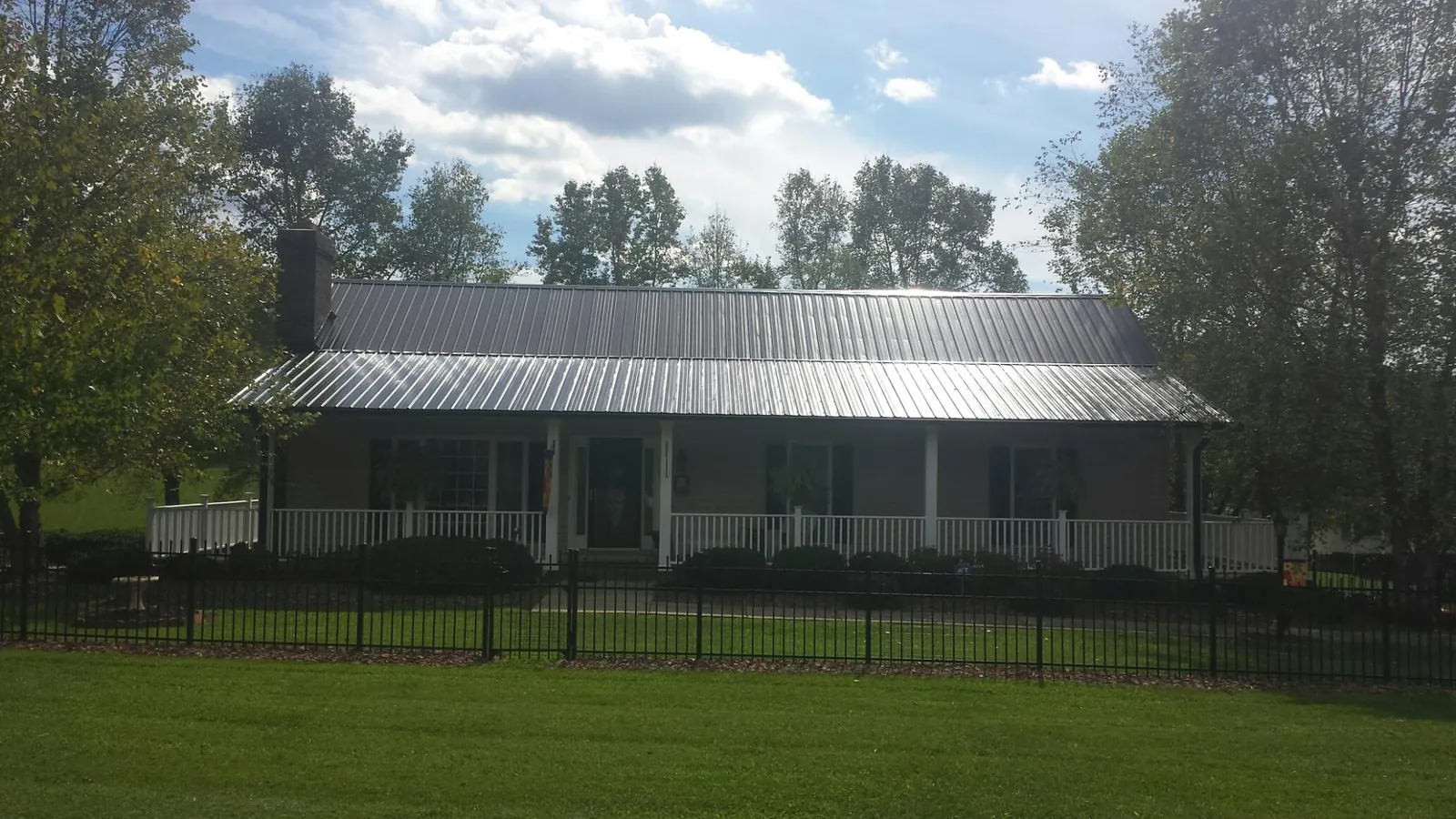 Gray metal roof on a brick ranch with a full width front porch — Gutter Guard Installation work by our crew in Washington Court House