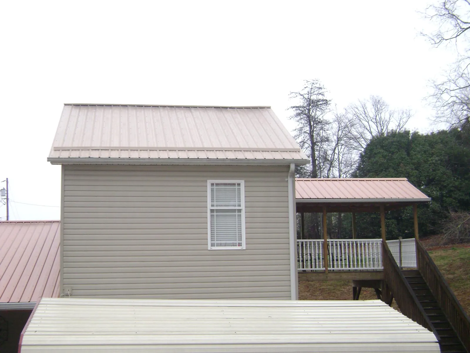 Tan metal roofs on a two story addition and attached porch, from a Roof Replacement job in Washington Court House