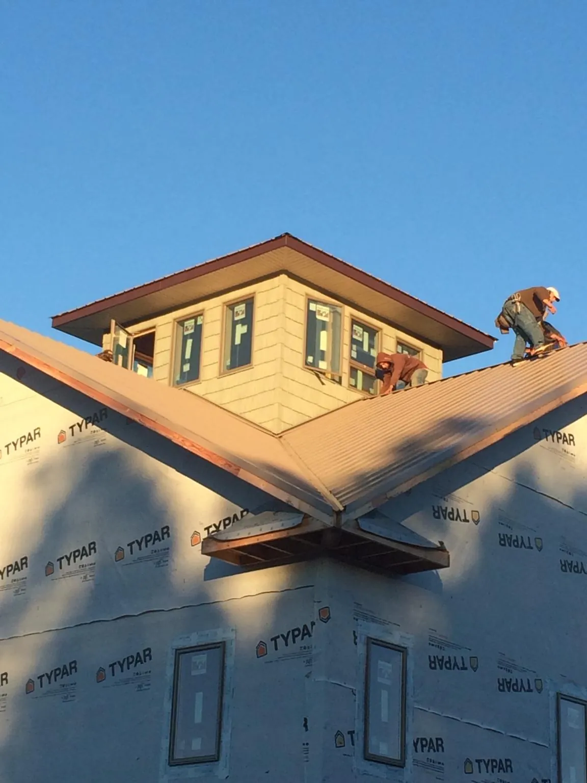 Roofers working around a rooftop cupola on a new metal roof at sunset — Roof Waterproofing in Washington Court House by Roofing Brothers